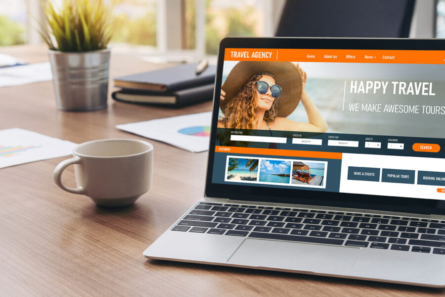 Desk with plant, coffee mug, and laptop showing online travel agency website