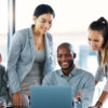 Team of four diverse co-workers smiling looking at a laptop