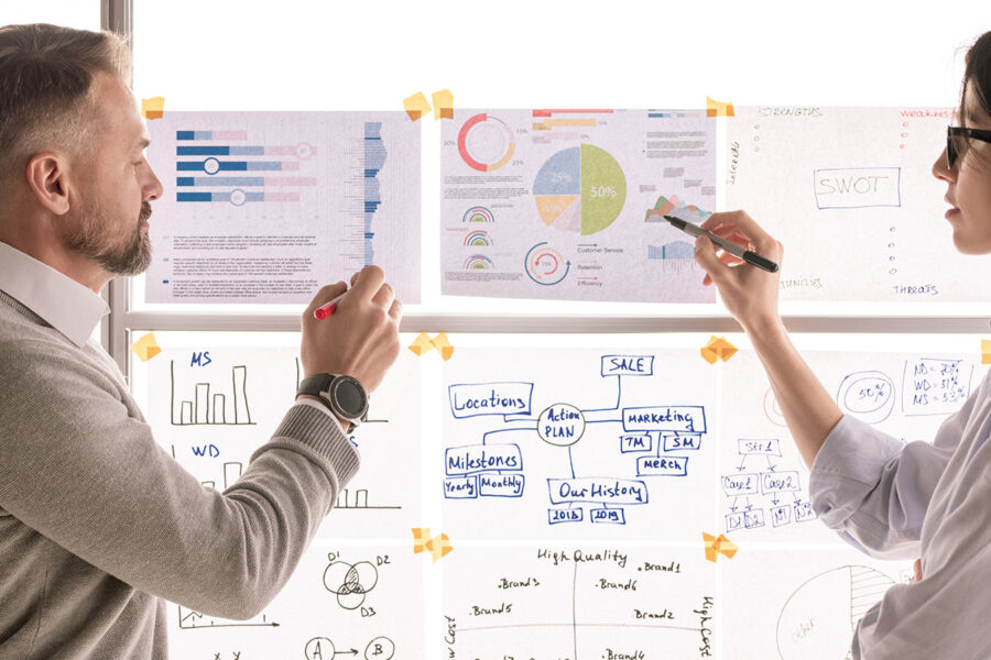 Two people at a white board talking about strategy
